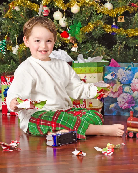 Młody chłopak rozpakowaniu prezenty na Boże Narodzenie rano — Zdjęcie stockowe