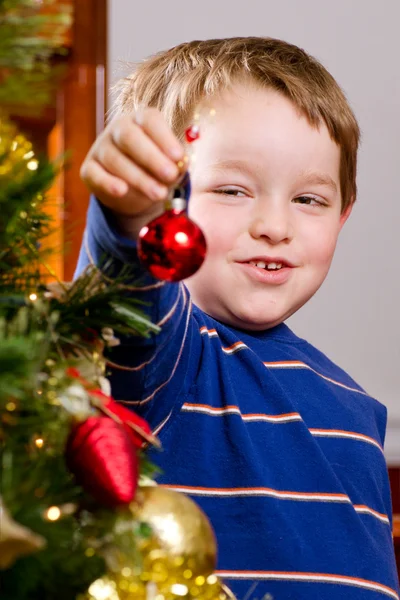 年轻的男孩装饰圣诞树的假期. 图库照片