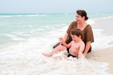 moeder en zoon spelen in surf op strand