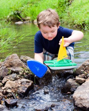 bahar ya da yaz Creek Park oyuncak tekneler ile oynayarak eğlenceli çocuk vardır