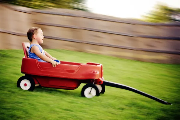 Young boy zooms downhill in wagon in image with motion blur. — Stock Photo, Image