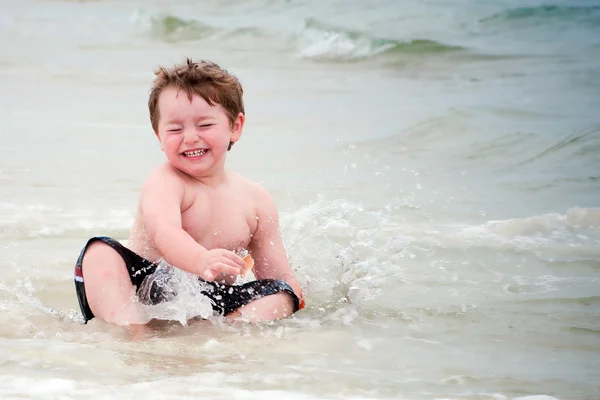 Young boy playing in surf at beach — Stock Photo, Image