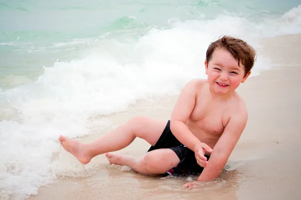 Jongen speelt in surf op strand — Stockfoto