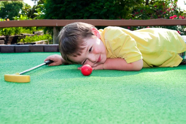 Niño juega mini golf en campo de putt putt . — Foto de Stock