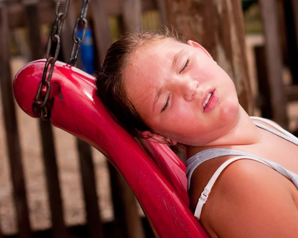 Κορίτσι ιδρώνει κάτω από τον ζεστό ήλιο στην παιδική χαρά. — Φωτογραφία Αρχείου