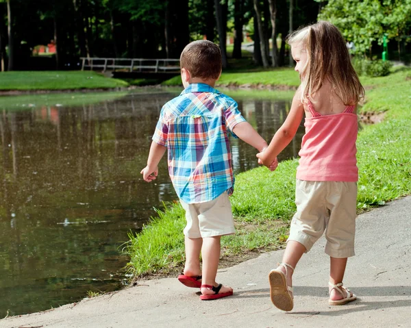 Chica hispana y niño caminan por el estanque . — Foto de Stock