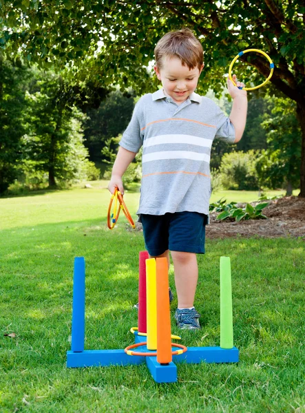 Young boy or kid playing ring toss outdoors at park during summer. — Stock Photo, Image