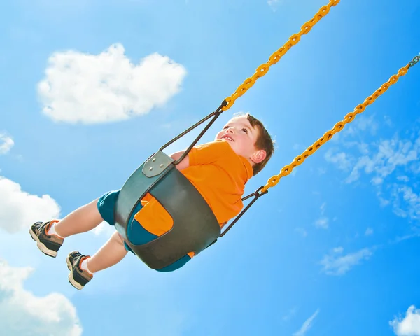 Pojke på swing på park med naturliga himlen ovan. — Stockfoto