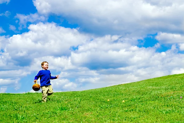 Easter egg hunt with young boy running with basket to collect Easter Eggs — Stock Photo, Image