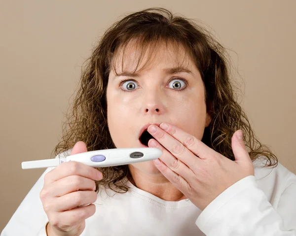 Mujer sorprendida, aturdida y sorprendida de mediana edad que sostiene una prueba de embarazo positiva —  Fotos de Stock