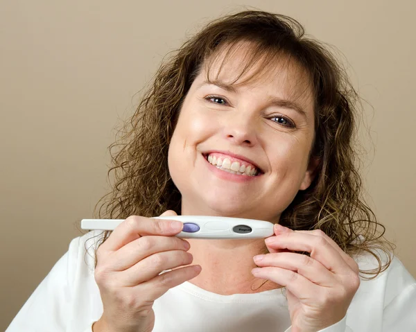 Happy middle-aged woman holding a positive pregnancy test — Stock Photo, Image
