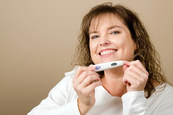 Mulher de meia-idade feliz segurando um teste de gravidez positivo — Fotografia de Stock