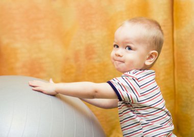 Baby boy playing with fit ball clipart