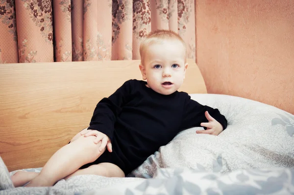 Baby boy posing on parents' bed in bedroom — Stock Photo, Image
