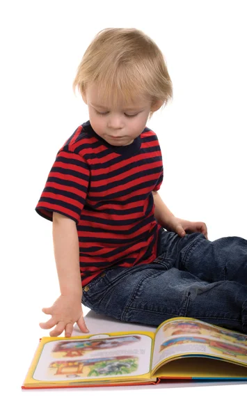 Junge sitzt mit Buch auf dem Boden Stockbild