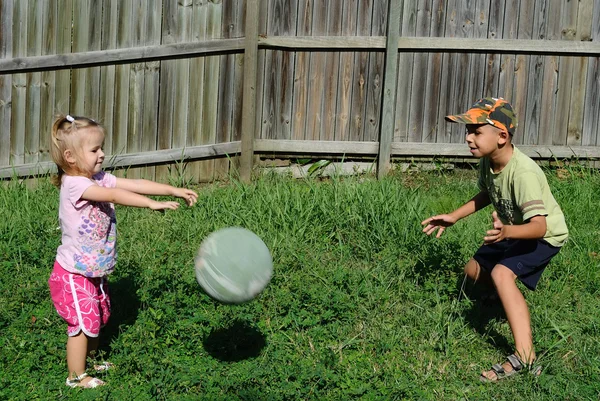 Two kids playing ball in a backyard — Stock Photo, Image