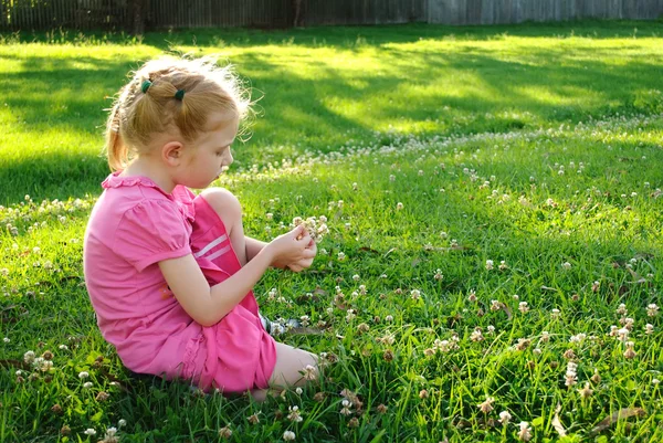 Young girl in pink picking up flowers in a field — Stock Photo, Image