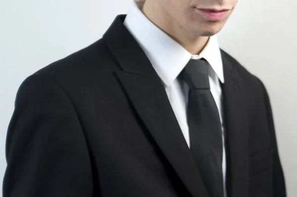 Jeune homme d'affaires beau en costume noir sur blanc . — Photo