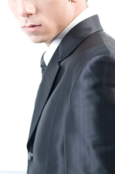 Junger hübscher Geschäftsmann im schwarzen Anzug auf weißem Grund. — Stockfoto