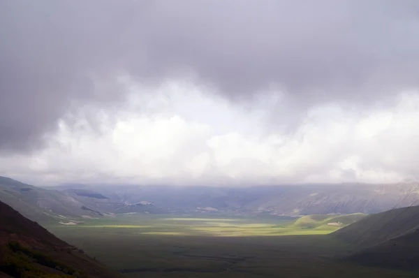 stock image Green meadow on declivity in mountain valley.