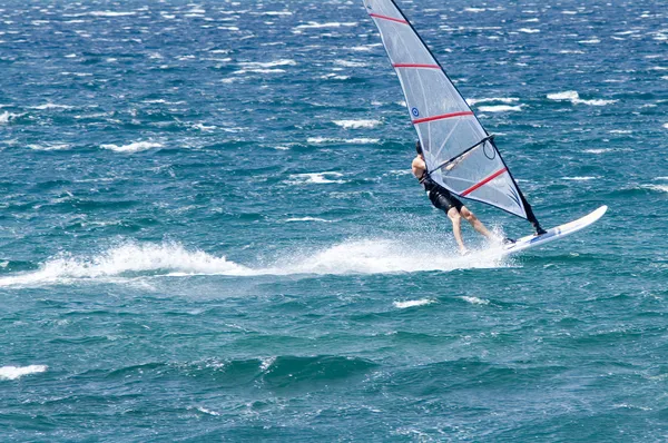 Windsurfista solitario en el océano cogiendo una ola — Foto de Stock