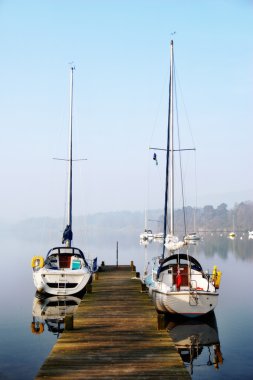 Pleasure yachts moored on rustic jetty clipart