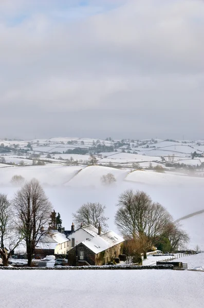 雪の中で小さな農家覆われた丘 — ストック写真