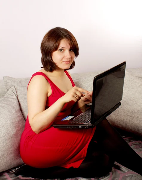 Attractive young women sitting on sofa and using laptop — Stock Photo, Image