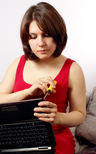 Attractive young women sitting on sofa with laptop and screwdriver — Stock Photo, Image