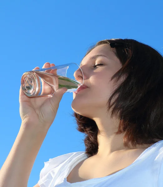 Mujer joven bebiendo agua en el cielo fondo —  Fotos de Stock