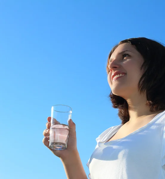 Jovem mulher bebendo água no céu fundo — Fotografia de Stock