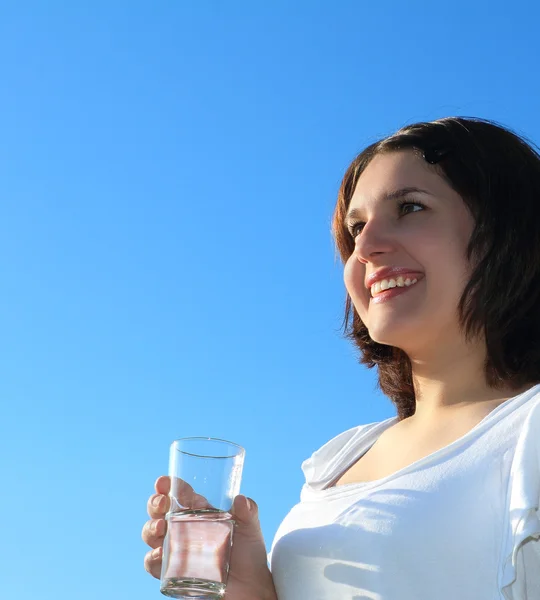 Mladá žena pitné vody na pozadí oblohy — Stock fotografie