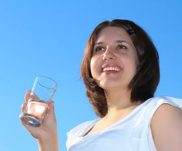 Jovem mulher bebendo água no céu fundo — Fotografia de Stock