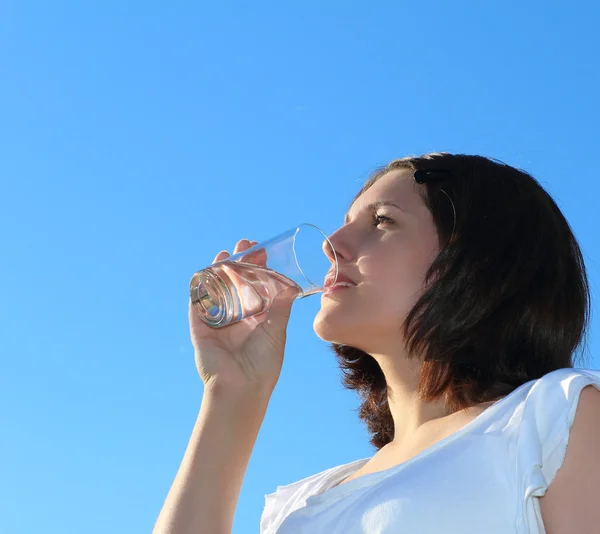 Genç kadın içme suyu gökyüzü arka plan üzerinde — Stok fotoğraf