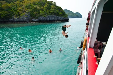 Travellers leap from the deck into the water. clipart