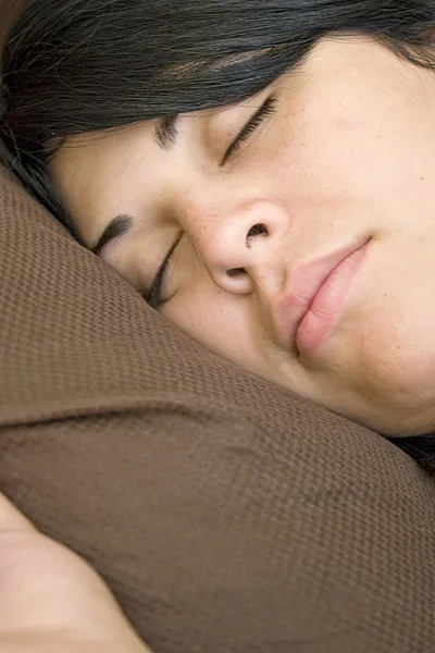 Mladá bruneta žena je tvrdě spal v posteli. — Stock fotografie