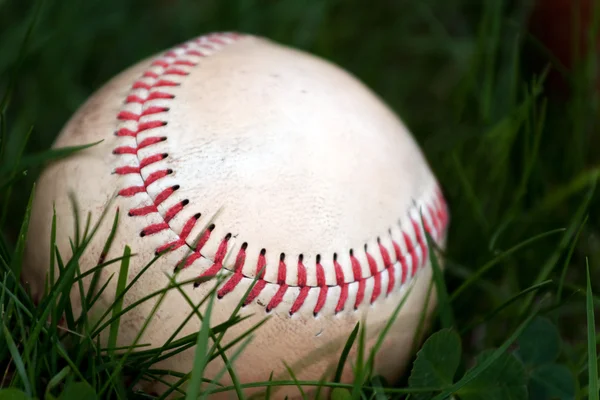 Oude honkbal in het gras — Stockfoto
