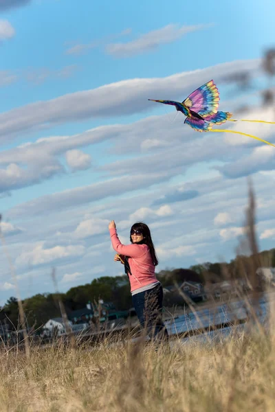 Mulher voando um papagaio na praia — Fotografia de Stock