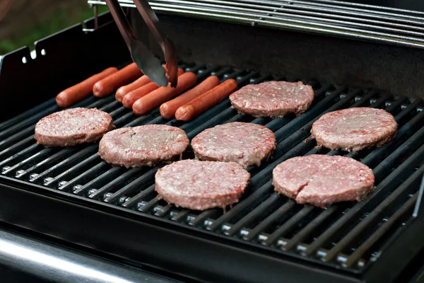 Párky v rohlíku a hamburgery na grilu — Stock fotografie