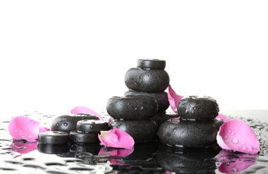 Spa stones with drops and rose petals on white background