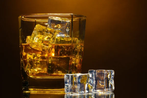 Kieliszek szkockiej whisky i lodu na brązowym tle — Zdjęcie stockowe