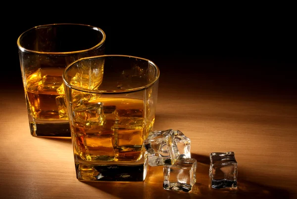 Twee glazen van scotch whisky en ijs op houten tafel — Stockfoto