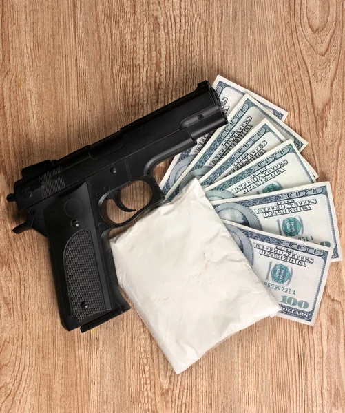 Cocaína em pacote, dólares e pistola sobre fundo de madeira — Fotografia de Stock