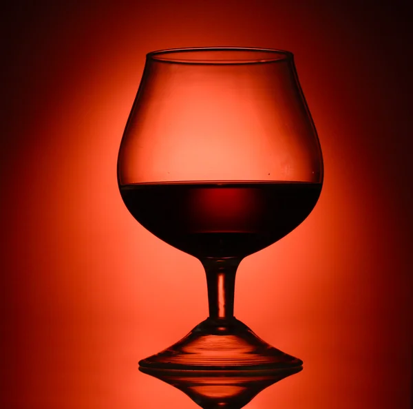 Gelas cognac pada latar belakang merah — Stok Foto