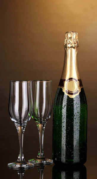 Fles champagne en bekers op bruine achtergrond — Stockfoto