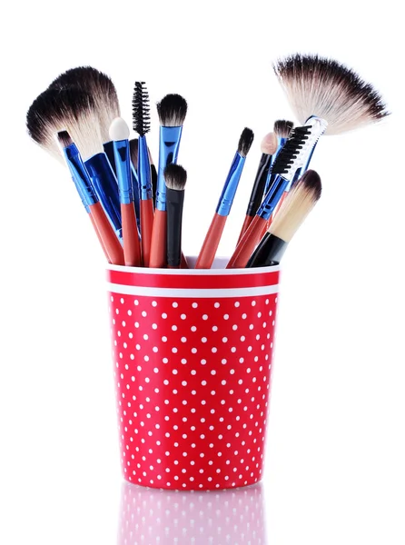 Pinceles de maquillaje en taza roja aislados en blanco — Foto de Stock