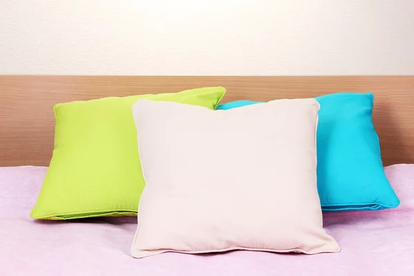 Яркие подушки на кровати на бежевом фоне — стоковое фото