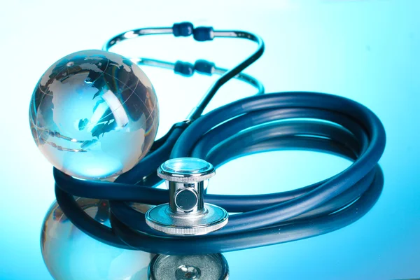 Globe and stethoscope on blue — Stock Photo, Image