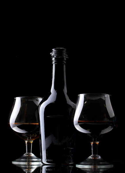 杯白兰地和黑色背景上瓶 — 图库照片