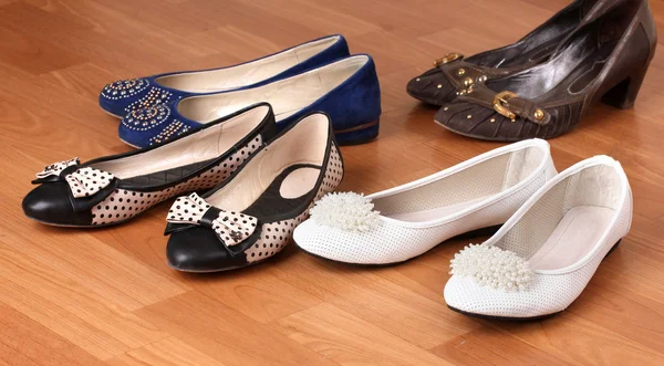Varios pares de zapatos planos femeninos sobre fondo de madera — Foto de Stock